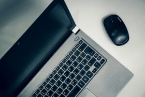 A close-up view of a silver laptop and wireless mouse on a smooth table, ideal for home office setups.